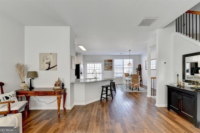 kitchen featuring kitchen peninsula, dark hardwood / wood-style floors, stainless steel refrigerator, and a kitchen bar