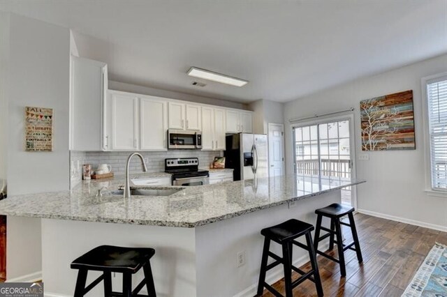 kitchen with a breakfast bar area, stainless steel appliances, kitchen peninsula, and a healthy amount of sunlight