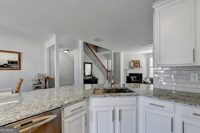 kitchen featuring light stone countertops, white cabinetry, and sink