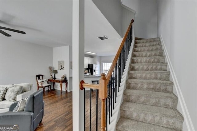 stairway with hardwood / wood-style floors and ceiling fan