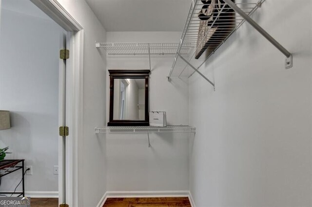 walk in closet with dark wood-type flooring