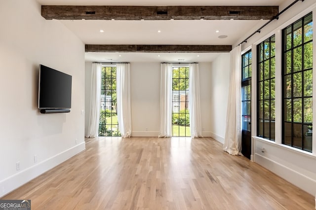 spare room with light hardwood / wood-style floors and beamed ceiling