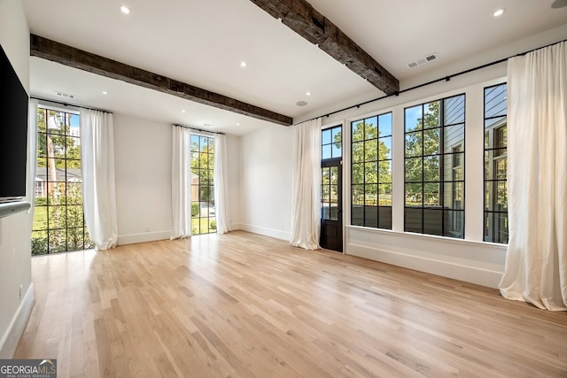 spare room featuring light hardwood / wood-style floors, plenty of natural light, and beam ceiling