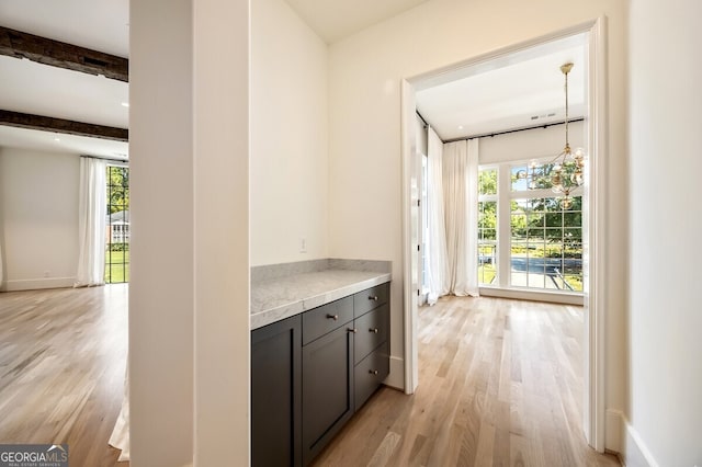 interior space featuring beam ceiling, plenty of natural light, light hardwood / wood-style floors, and a chandelier