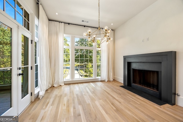 unfurnished living room featuring a notable chandelier and light hardwood / wood-style flooring