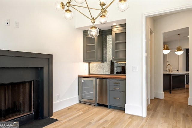 kitchen featuring gray cabinets, stainless steel fridge, light wood-type flooring, wine cooler, and backsplash