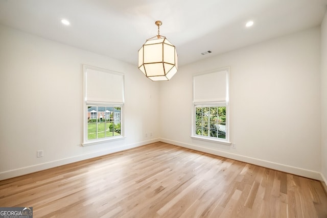 empty room with plenty of natural light and light hardwood / wood-style floors