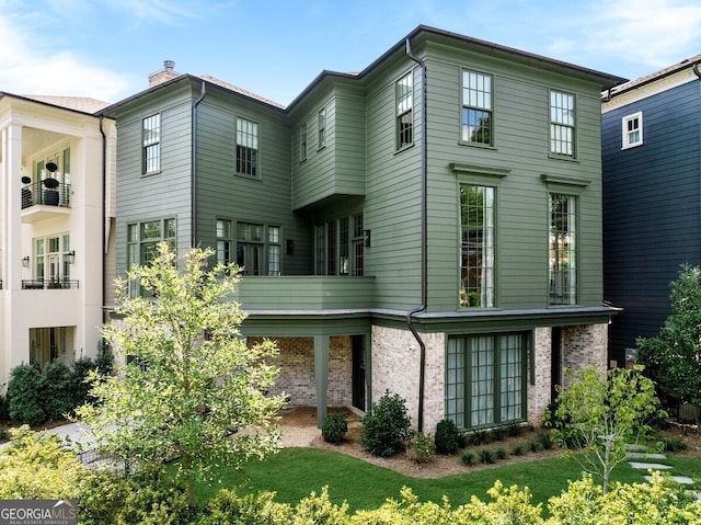 rear view of house featuring a balcony and a yard