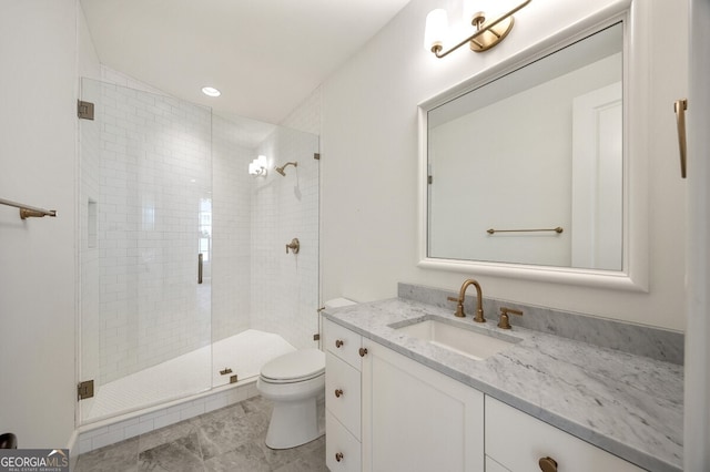 bathroom featuring vanity, a shower with door, and toilet