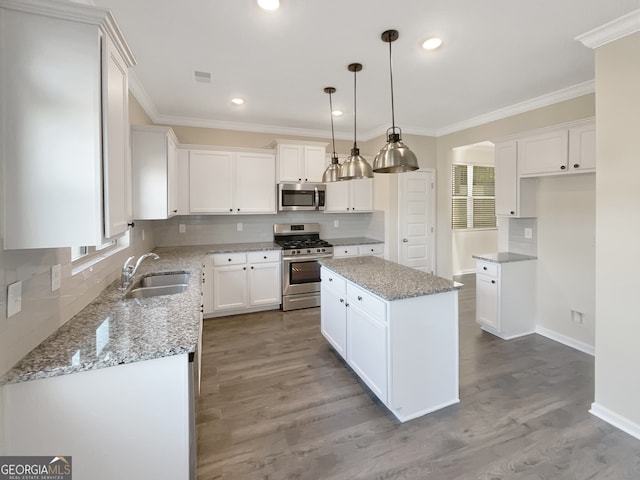 kitchen featuring white cabinets, stainless steel appliances, sink, and a kitchen island