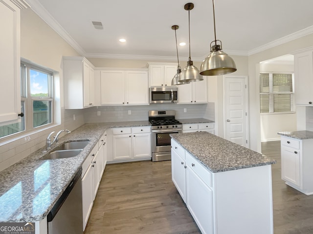 kitchen featuring stainless steel appliances, sink, a center island, and white cabinetry