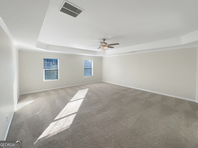 empty room featuring ceiling fan, light colored carpet, a raised ceiling, and ornamental molding