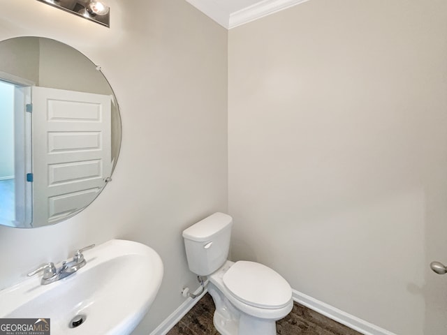 bathroom with wood-type flooring, ornamental molding, sink, and toilet