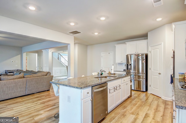 kitchen featuring white cabinets, appliances with stainless steel finishes, sink, and a kitchen island with sink