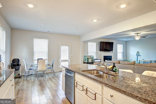 kitchen with ceiling fan, sink, light hardwood / wood-style flooring, dishwasher, and dark stone counters