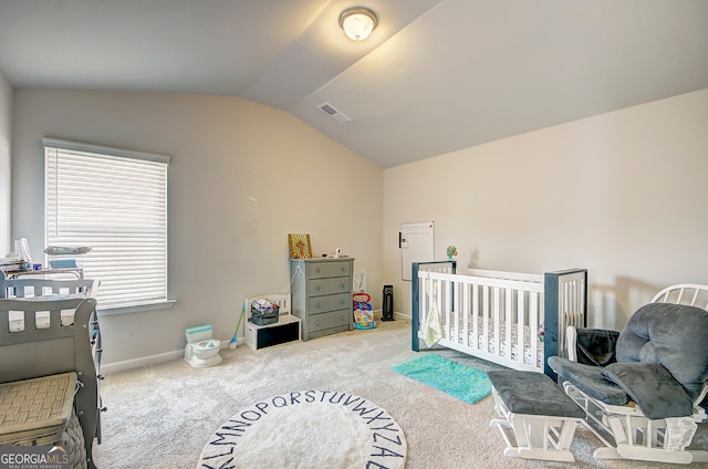 carpeted bedroom featuring a nursery area and vaulted ceiling