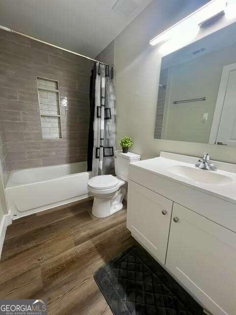 full bathroom featuring shower / bath combination with curtain, wood-type flooring, vanity, and toilet