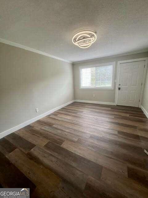 unfurnished dining area featuring crown molding, dark hardwood / wood-style floors, and a textured ceiling