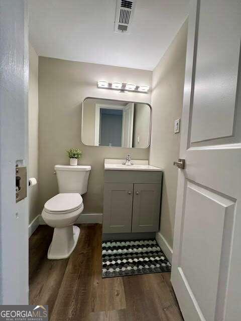 bathroom with wood-type flooring, vanity, and toilet