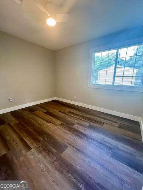 empty room featuring dark hardwood / wood-style flooring and ceiling fan