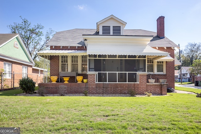 rear view of house featuring a sunroom and a lawn