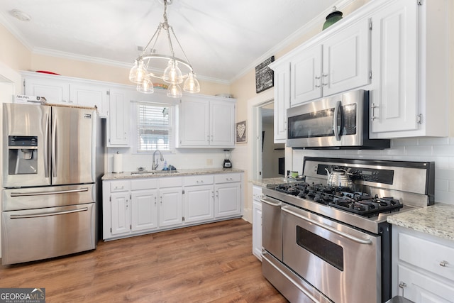 kitchen featuring hanging light fixtures, sink, white cabinetry, stainless steel appliances, and hardwood / wood-style floors