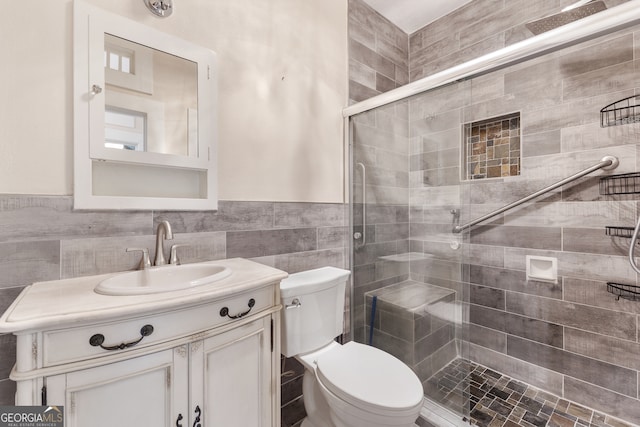 bathroom with tile walls, a shower with door, vanity, and toilet