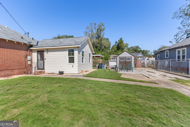 rear view of house featuring an outdoor structure and a lawn