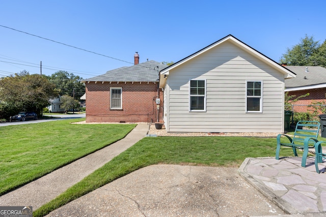 back of house with a patio and a lawn