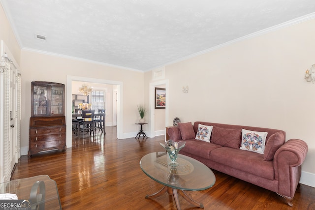 living room featuring ornamental molding, an inviting chandelier, and dark hardwood / wood-style floors