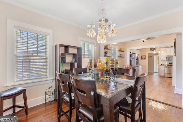 dining space featuring ornamental molding, light wood-type flooring, and a healthy amount of sunlight