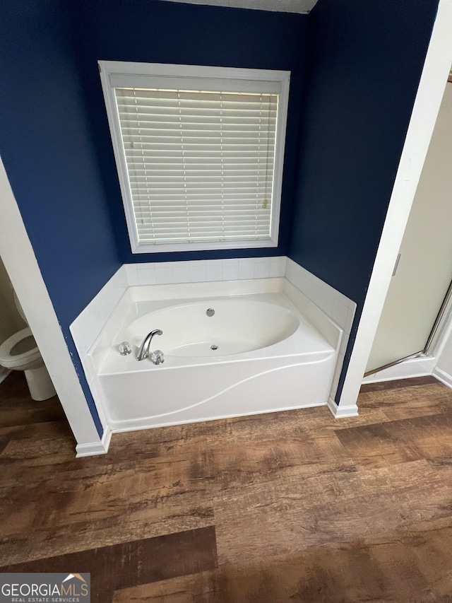 bathroom with wood-type flooring, plus walk in shower, and toilet