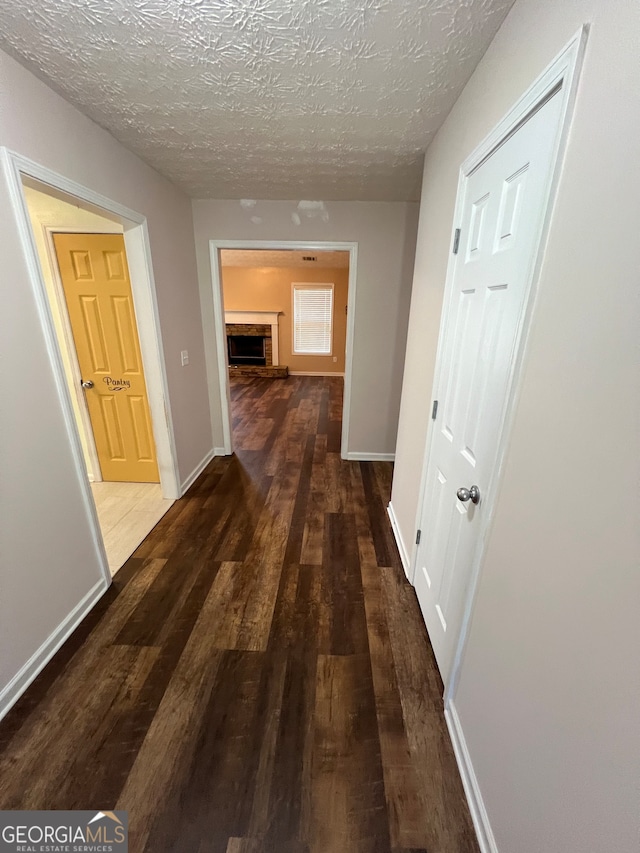 corridor featuring dark hardwood / wood-style flooring and a textured ceiling