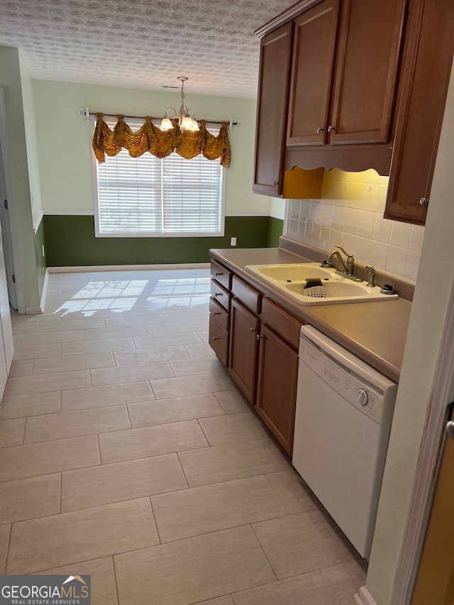 kitchen featuring sink, a textured ceiling, decorative light fixtures, dishwasher, and an inviting chandelier