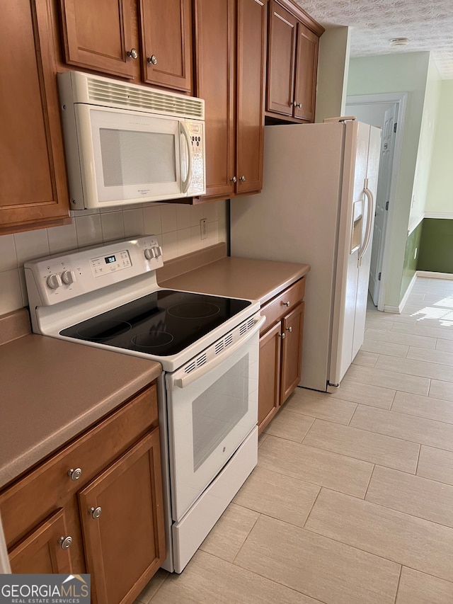 kitchen with decorative backsplash, white appliances, and a textured ceiling