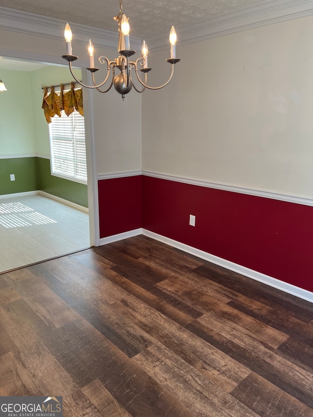 empty room featuring an inviting chandelier, hardwood / wood-style flooring, crown molding, and a textured ceiling