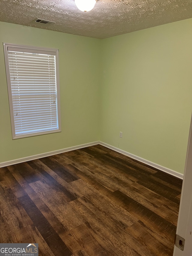 empty room featuring a textured ceiling and dark hardwood / wood-style flooring