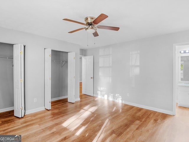 unfurnished bedroom with ensuite bath, multiple closets, and light hardwood / wood-style floors