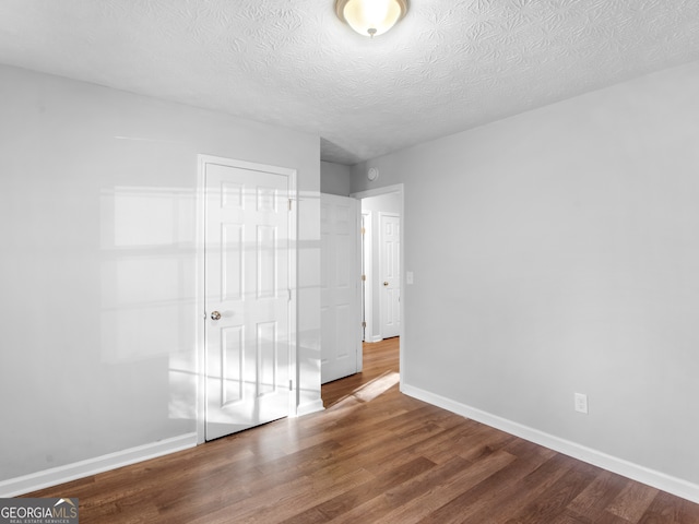 unfurnished bedroom with hardwood / wood-style floors, a textured ceiling, and a closet