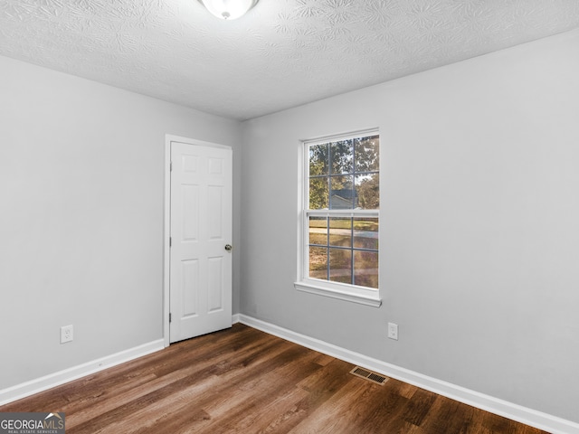 unfurnished room featuring a textured ceiling and dark wood-type flooring