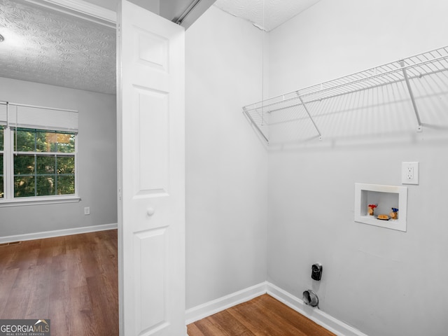 clothes washing area with hardwood / wood-style floors, a textured ceiling, and washer hookup