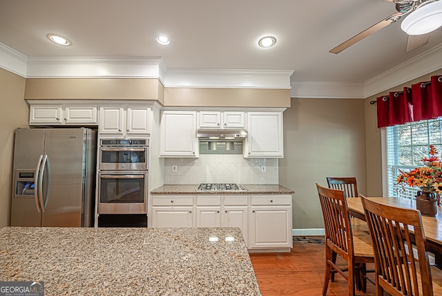 kitchen with crown molding, white cabinets, appliances with stainless steel finishes, and light stone counters