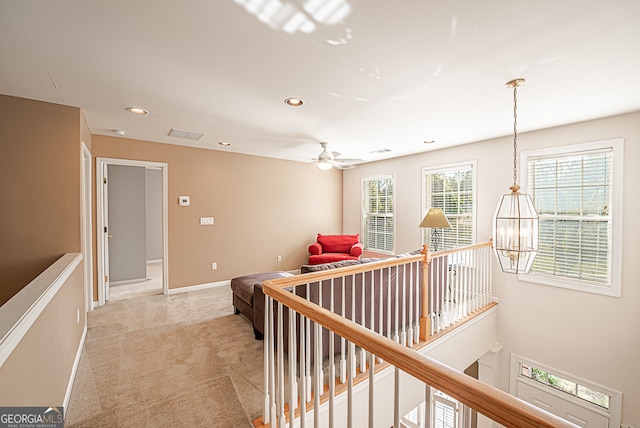 hall with an inviting chandelier and light carpet