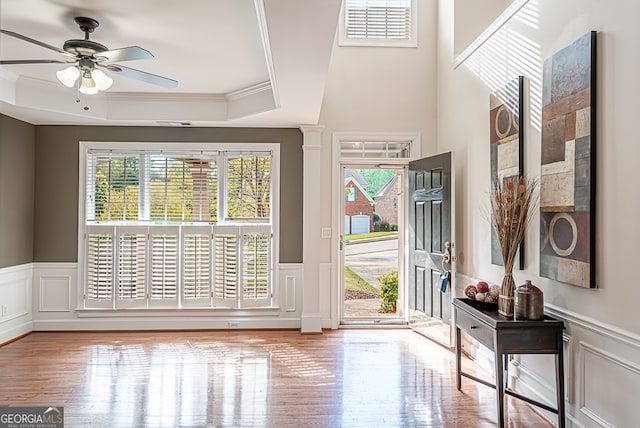 foyer entrance with ornamental molding, hardwood / wood-style flooring, ceiling fan, and a raised ceiling