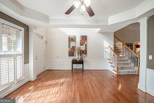 foyer with ornate columns, crown molding, hardwood / wood-style floors, and ceiling fan