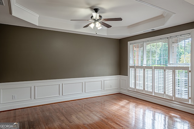 unfurnished room with ornamental molding, a tray ceiling, light wood-type flooring, and ceiling fan