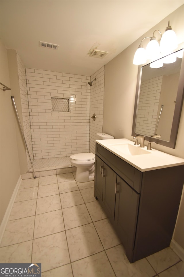 bathroom with a tile shower, tile patterned floors, vanity, and toilet