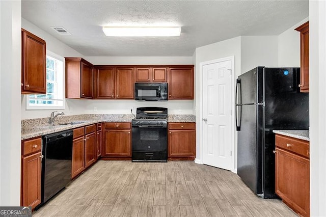 kitchen featuring light hardwood / wood-style floors, sink, light stone counters, black appliances, and a textured ceiling