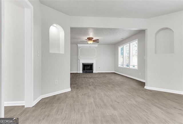 unfurnished living room featuring light hardwood / wood-style floors, a textured ceiling, and ceiling fan