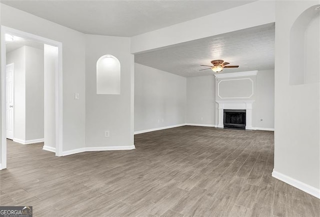 unfurnished living room with ceiling fan, wood-type flooring, and a textured ceiling